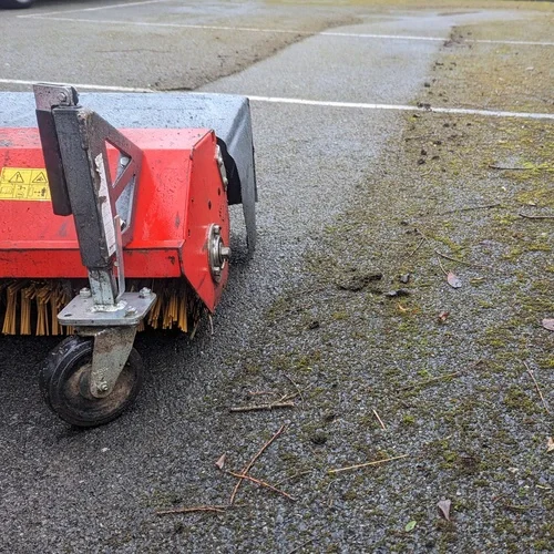 Kersten pedestrian sweeper removing moss from a hard-surface sports court