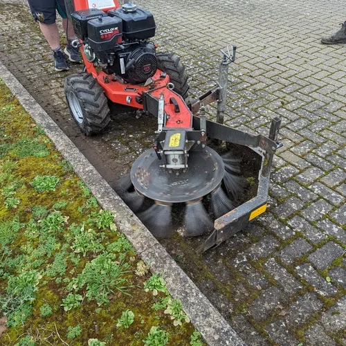 Kersten weed brush removing compacted soil and growth from a block-paved kerb edge
